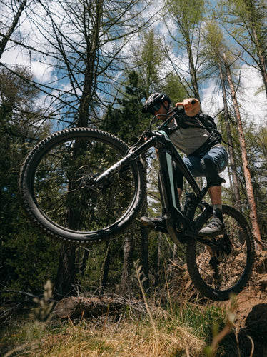 E_mountain bike flying across a berm with its rider.. 